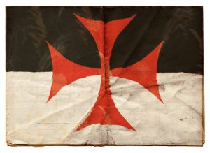 "The flag of the Knights Templar on an old folded sheet of paper.The Knights Templar where a medieval Christian military order, formed at the time of Crusades, the entire Order was forcibly disbanded 1312. But myths and rumours persist as to their continued existence."